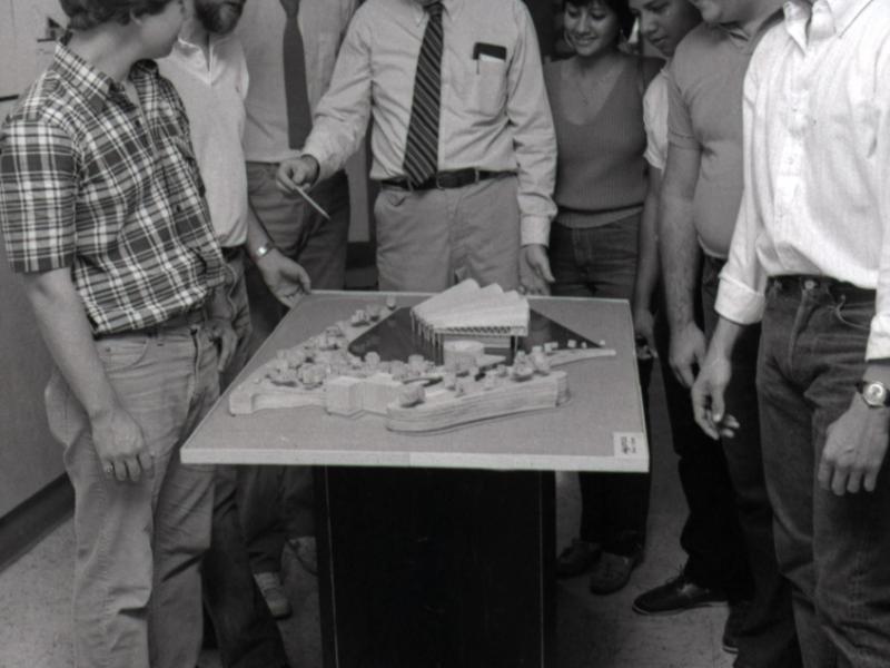 Several people standing over a model building
