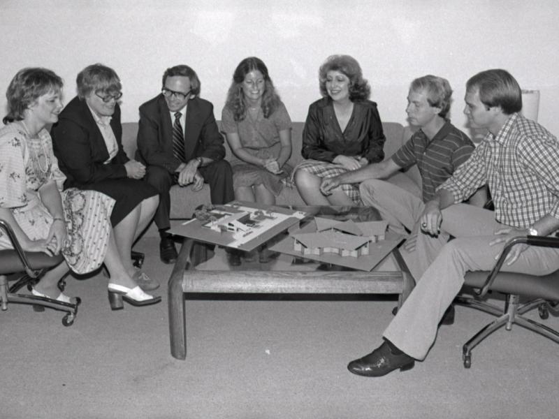 Several people sitting around a table with model buildings